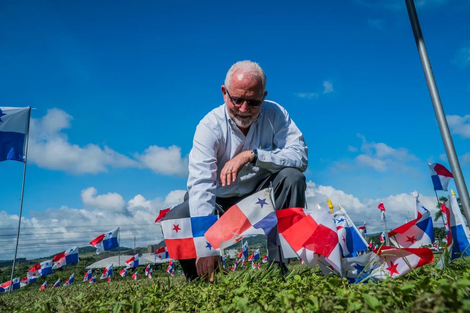 Hombre coloca diferentes banderines de Panamá en un pedazo de tierra