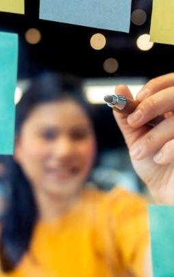 Mujer escribe ideas en post it en un tablero durante una charla en Ciudad del Saber