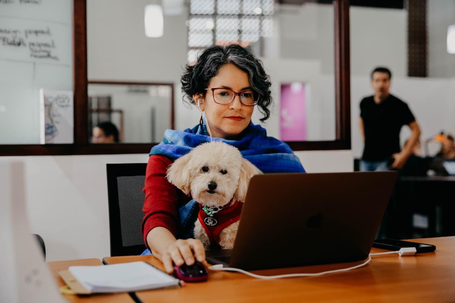 Mujer trabaja en su computador mientras la acompaña su mascota de soporte emocional