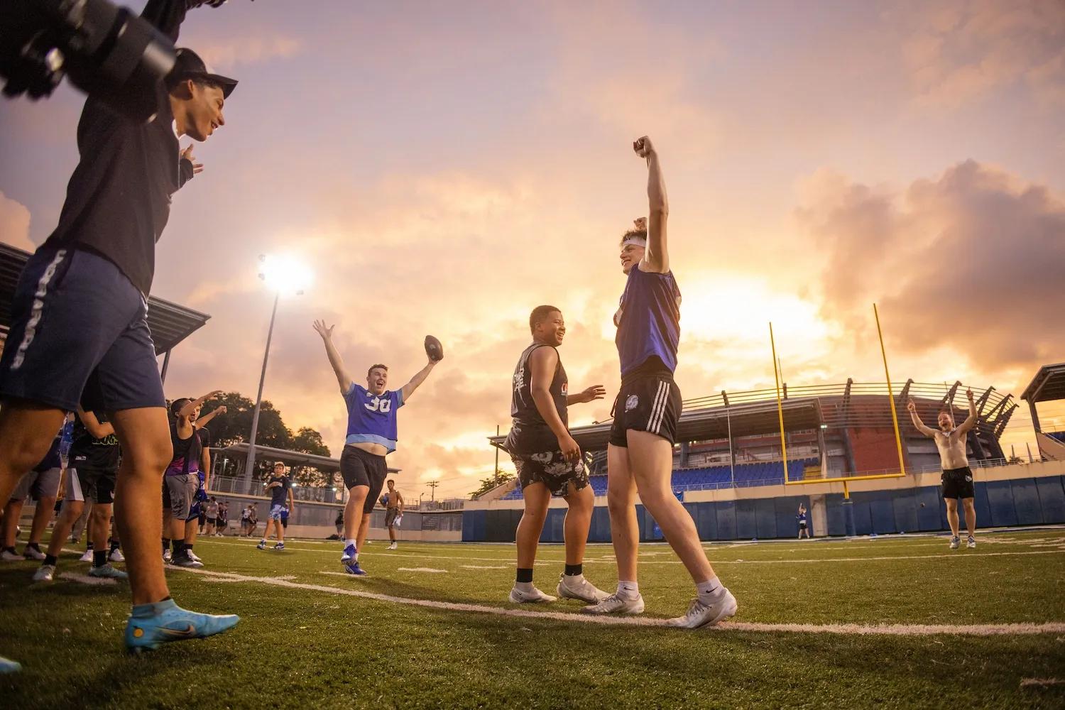 Personas en símbolo de victoria levantan sus manos festejando en una cancha